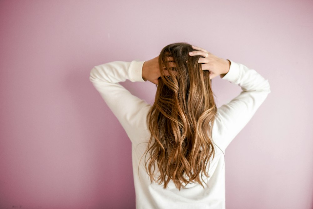 Lang golvend haar tegen een roze muur