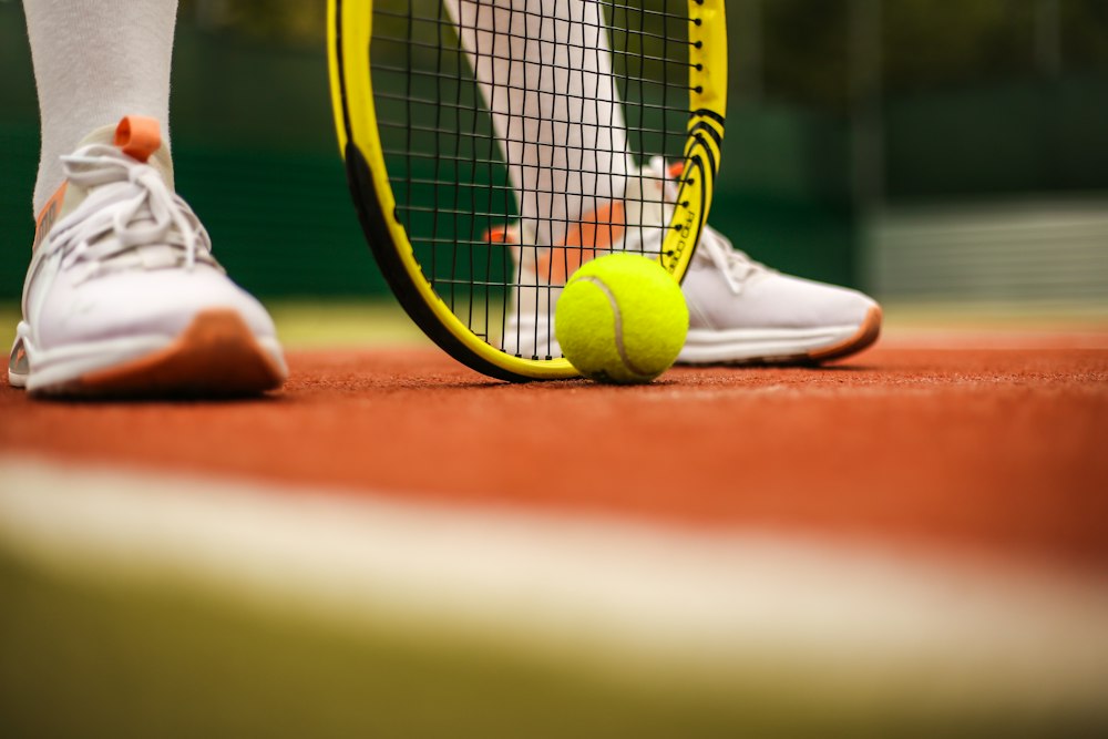 Tennisbal, racket en schoenen op gravel