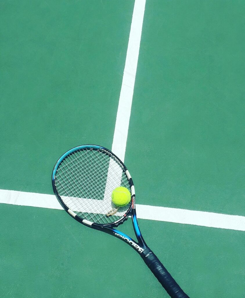 Tennisracket en bal op een groene baan